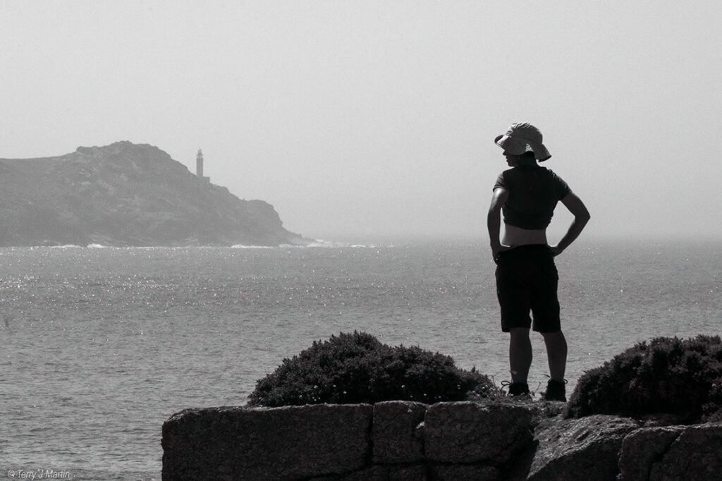 A person looking into the distance across the sea, in black and white