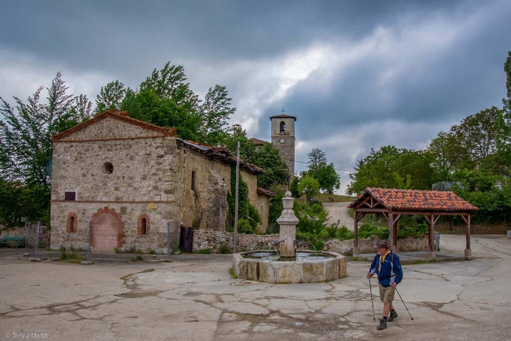 A man walking by a well in a village