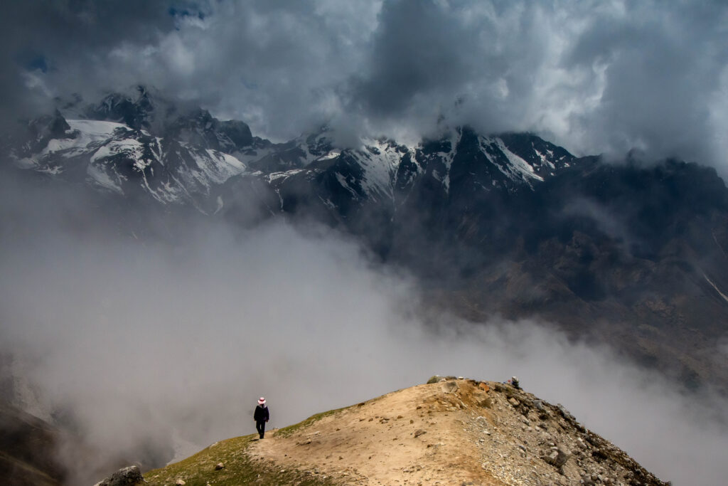 A person descending from Tsergo Ri into a misty Langtang Valley