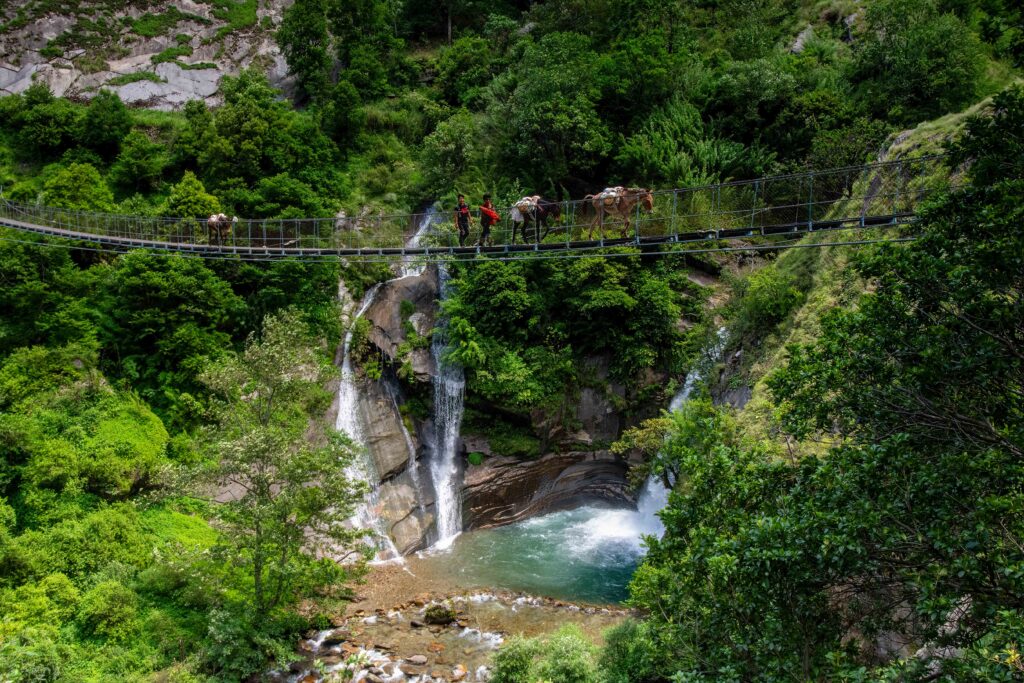 Two people and their pack mules journeying across a bridge