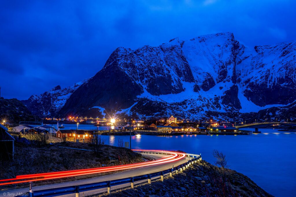 A long exposure photo of night traffic near a village on the Lofoten Islands in Norway